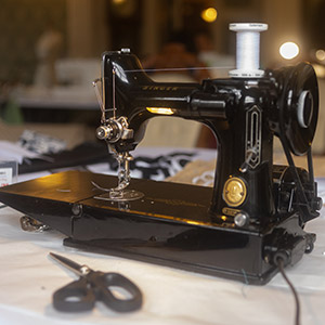 A close up photograph of a small scale, Singer Sewing machine on a desk with some scissors in front of it.